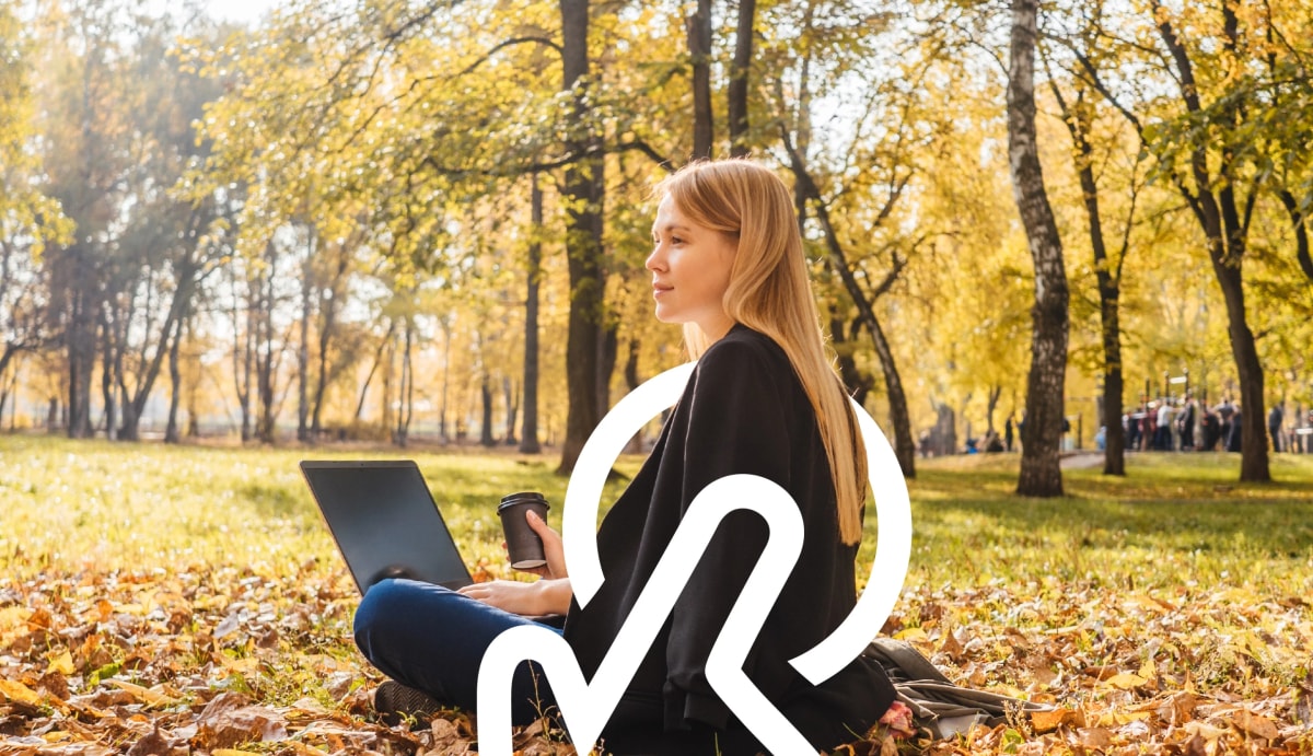 Woman sitting in nature with laptop and coffee